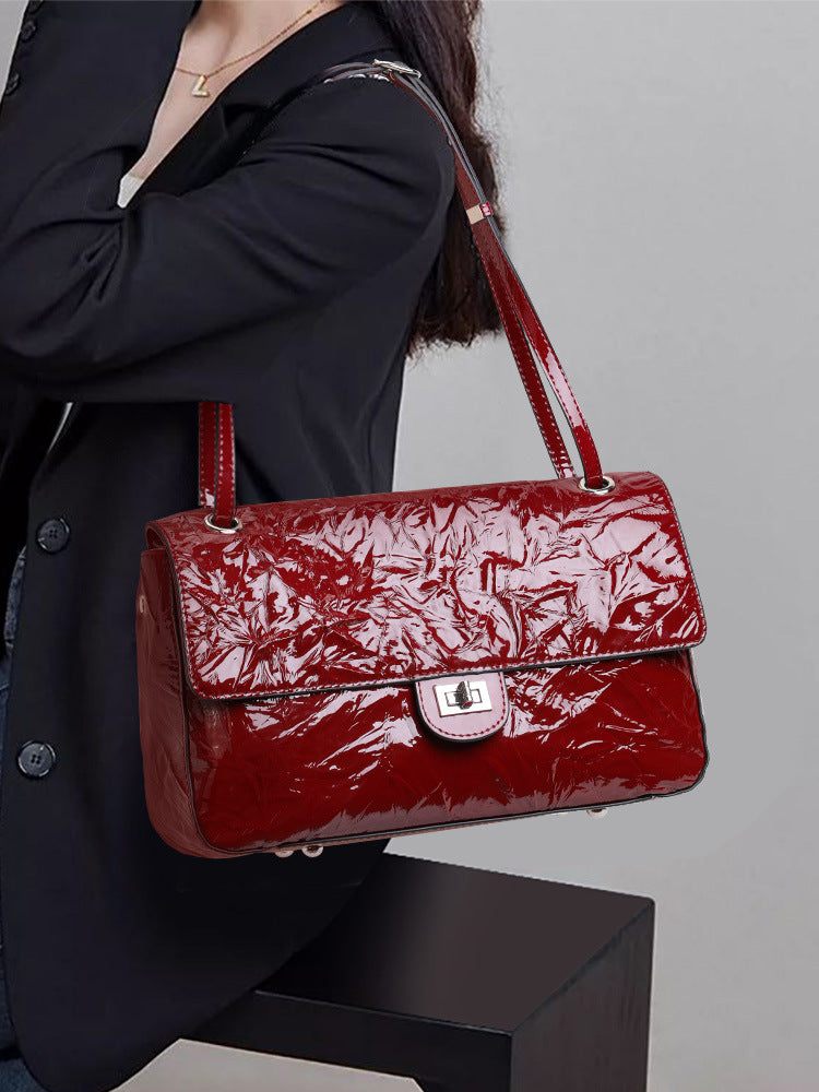 The Statement Flap Bag, held in the hand in wine
