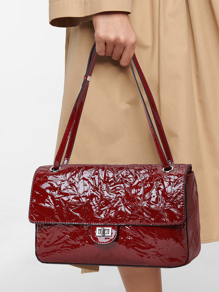 The Statement Flap Bag, carried on the shoulder in wine
